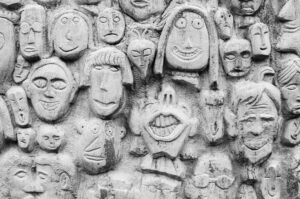 Wall with carved funny faces representing different expressions and personalities, illustrating the concept of distinct character voices in writing.